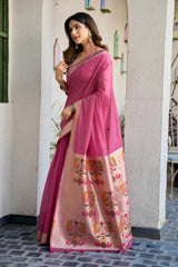 Woman wearing a pink saree with floral patterns indoors.