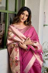 Woman wearing a pink saree with floral patterns indoors.