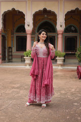 Woman in a pink traditional outfit standing in front of a colorful architectural background