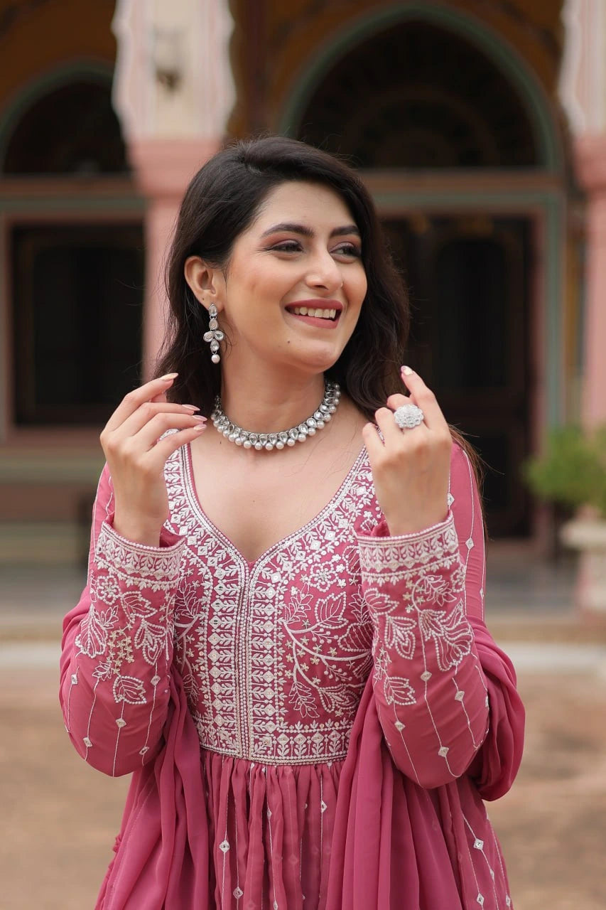 Woman in a pink embroidered outfit with jewelry outdoors