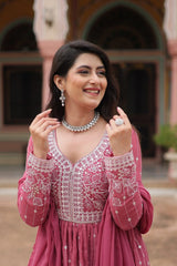 Woman in a pink embroidered outfit with jewelry outdoors