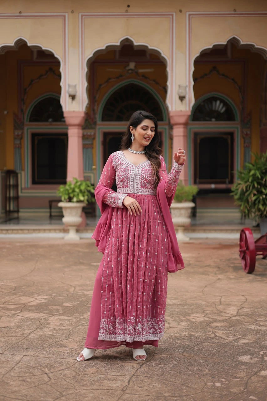 Woman in a pink traditional outfit standing in front of an architectural building.
