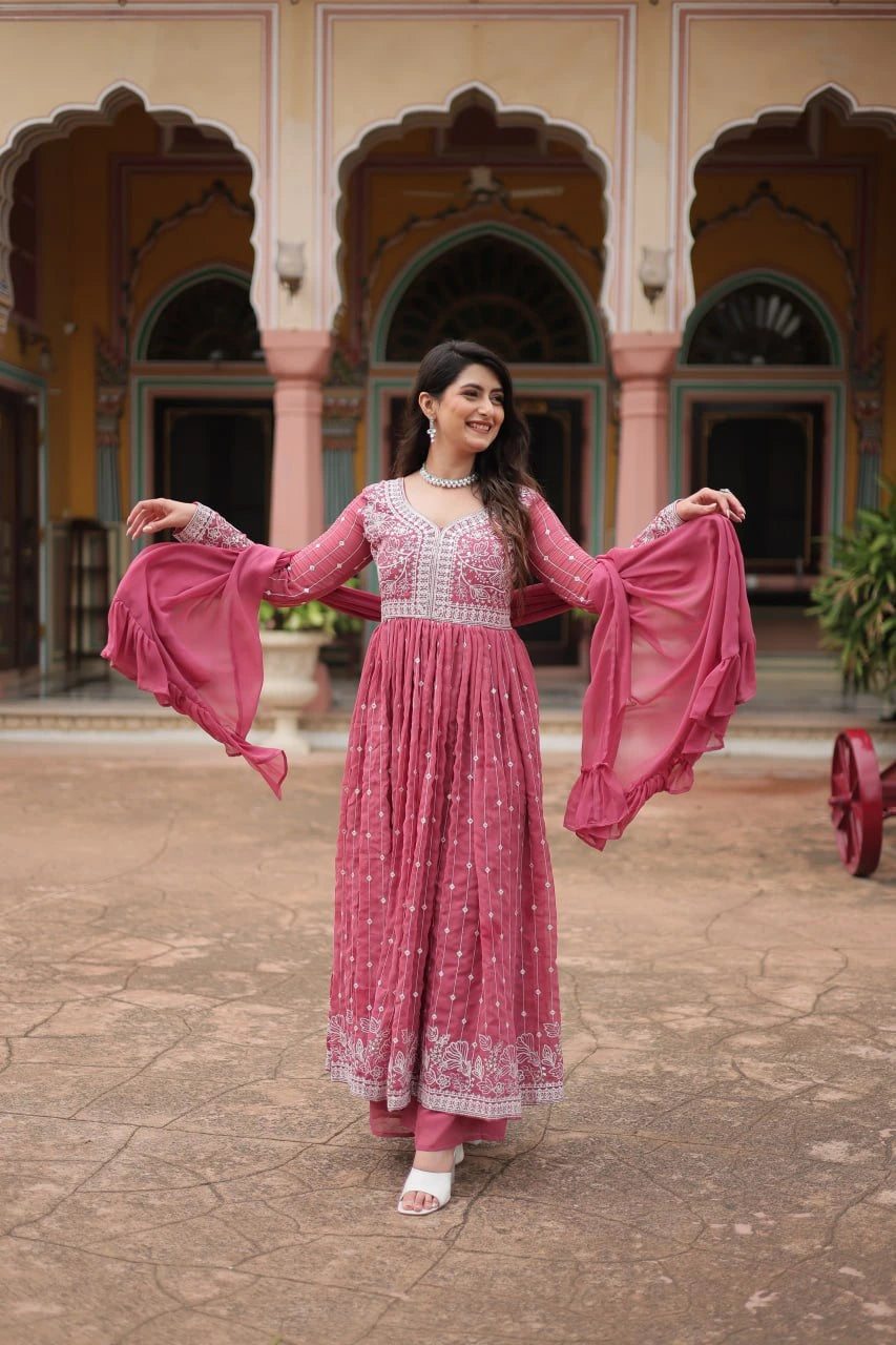 Woman in a pink traditional outfit standing in front of an architectural building.