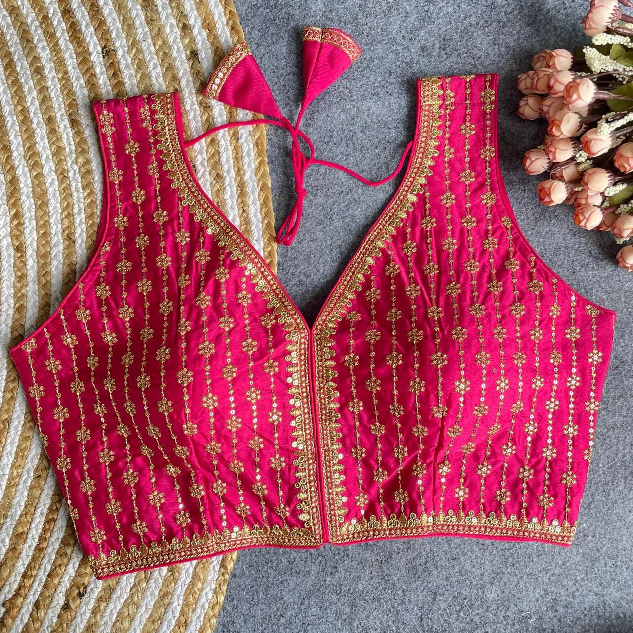 Pink embroidered top on a textured surface with flowers.