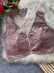Pink sequin bralette on a textured surface with flowers in the corner