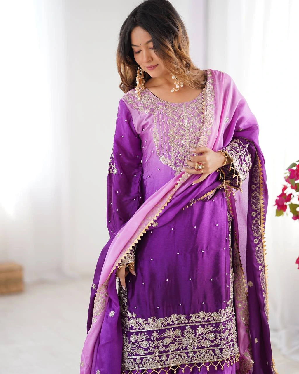 Woman wearing a purple embroidered traditional outfit with a white background