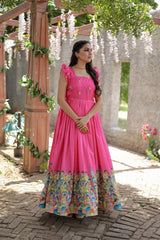 Woman in a pink dress with floral pattern standing under a decorated archway.
