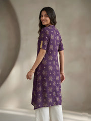Woman wearing a purple kurta with white pants against a neutral background