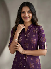 Woman wearing a purple patterned shirt against a neutral background