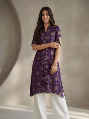 Woman wearing a purple floral kurta with white pants against a neutral background