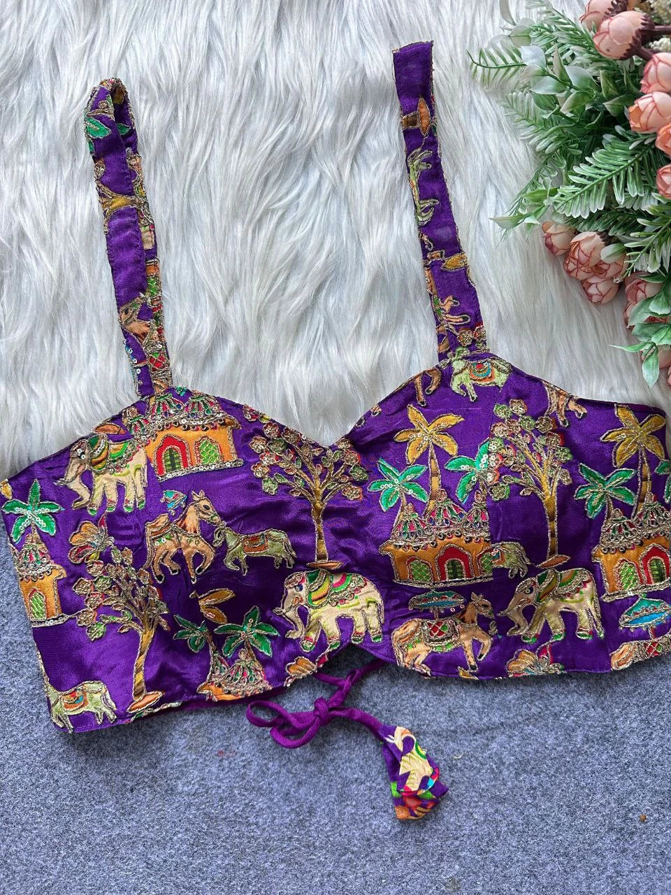 Purple embroidered bikini top with colorful patterns on a textured surface.