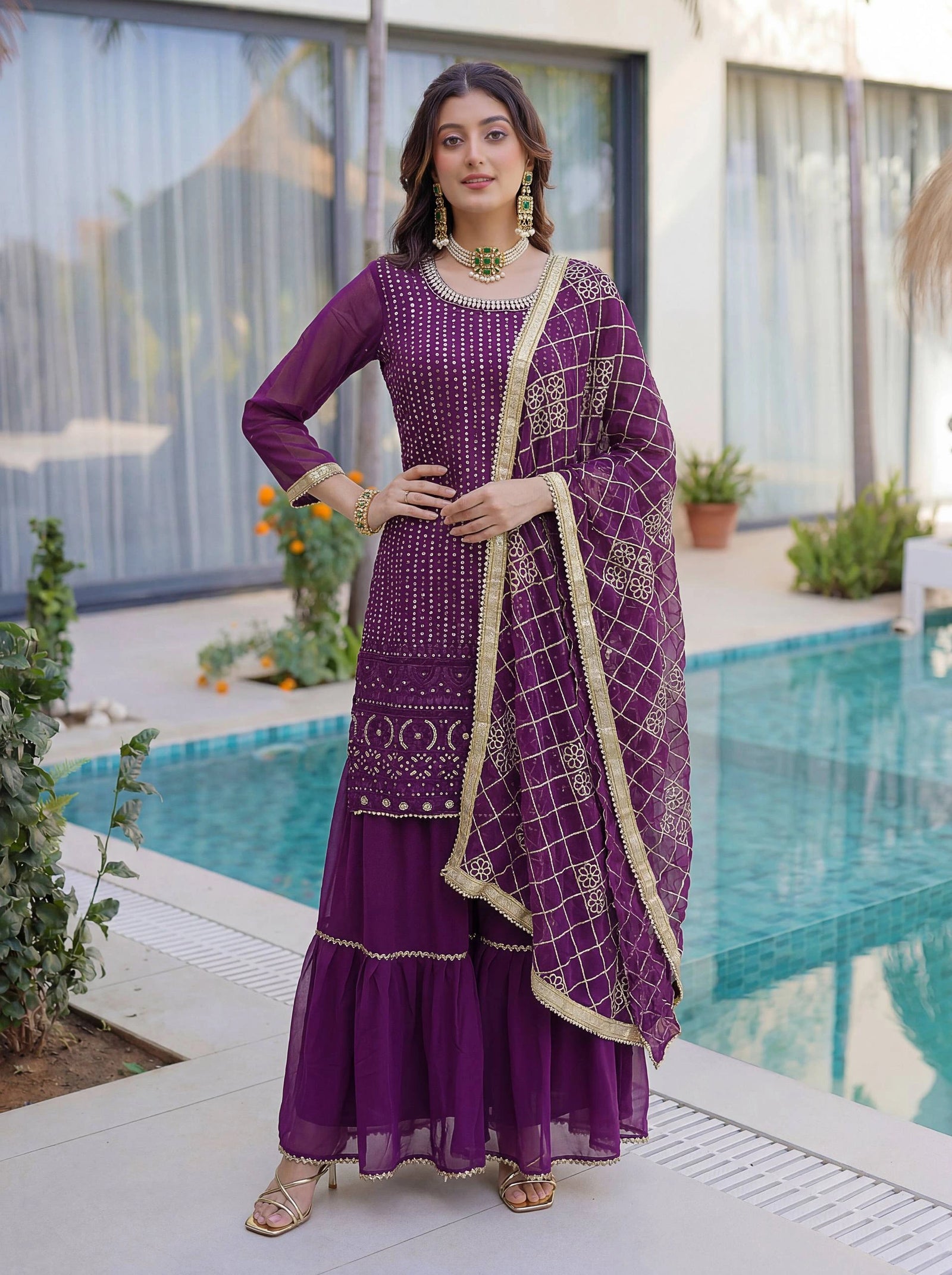 Woman in a purple traditional outfit standing by a pool