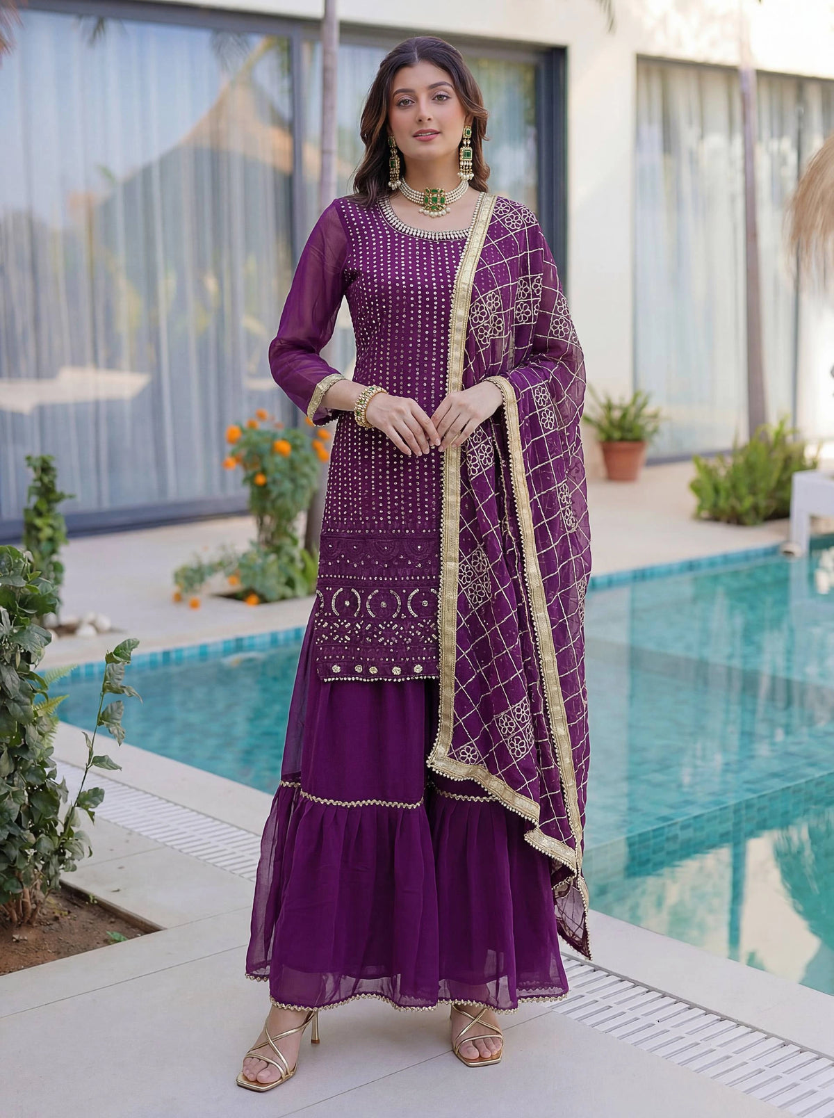 Woman in a purple traditional outfit standing by a poolside.