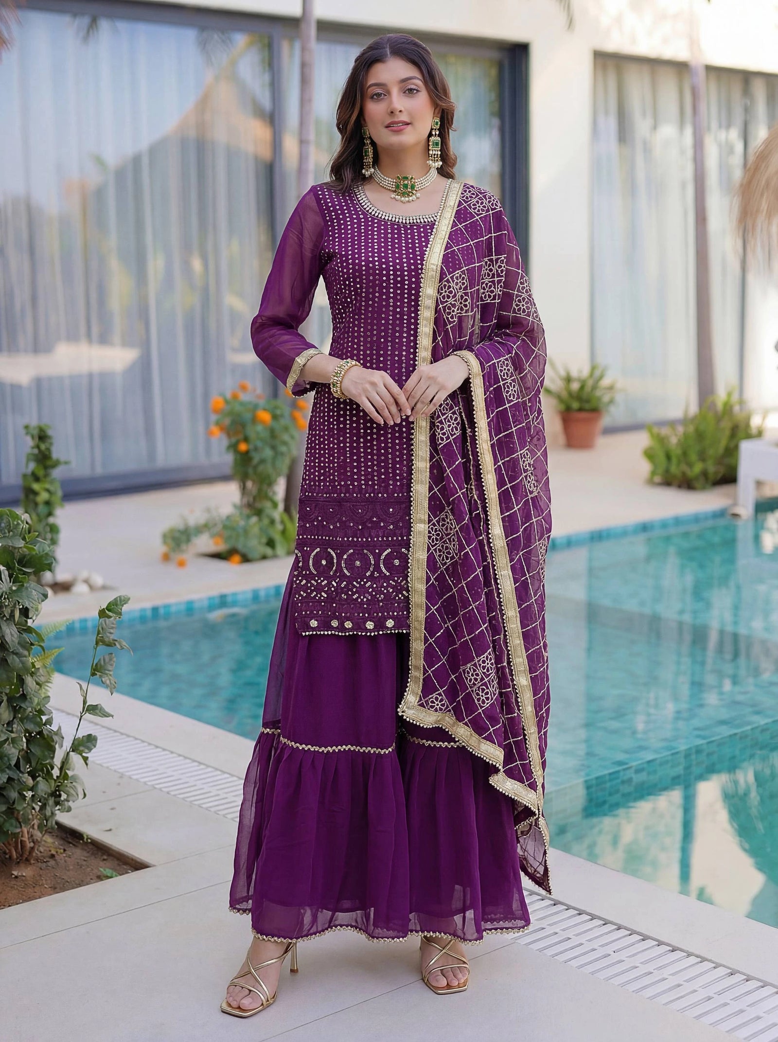 Woman in a purple traditional outfit standing by a poolside.