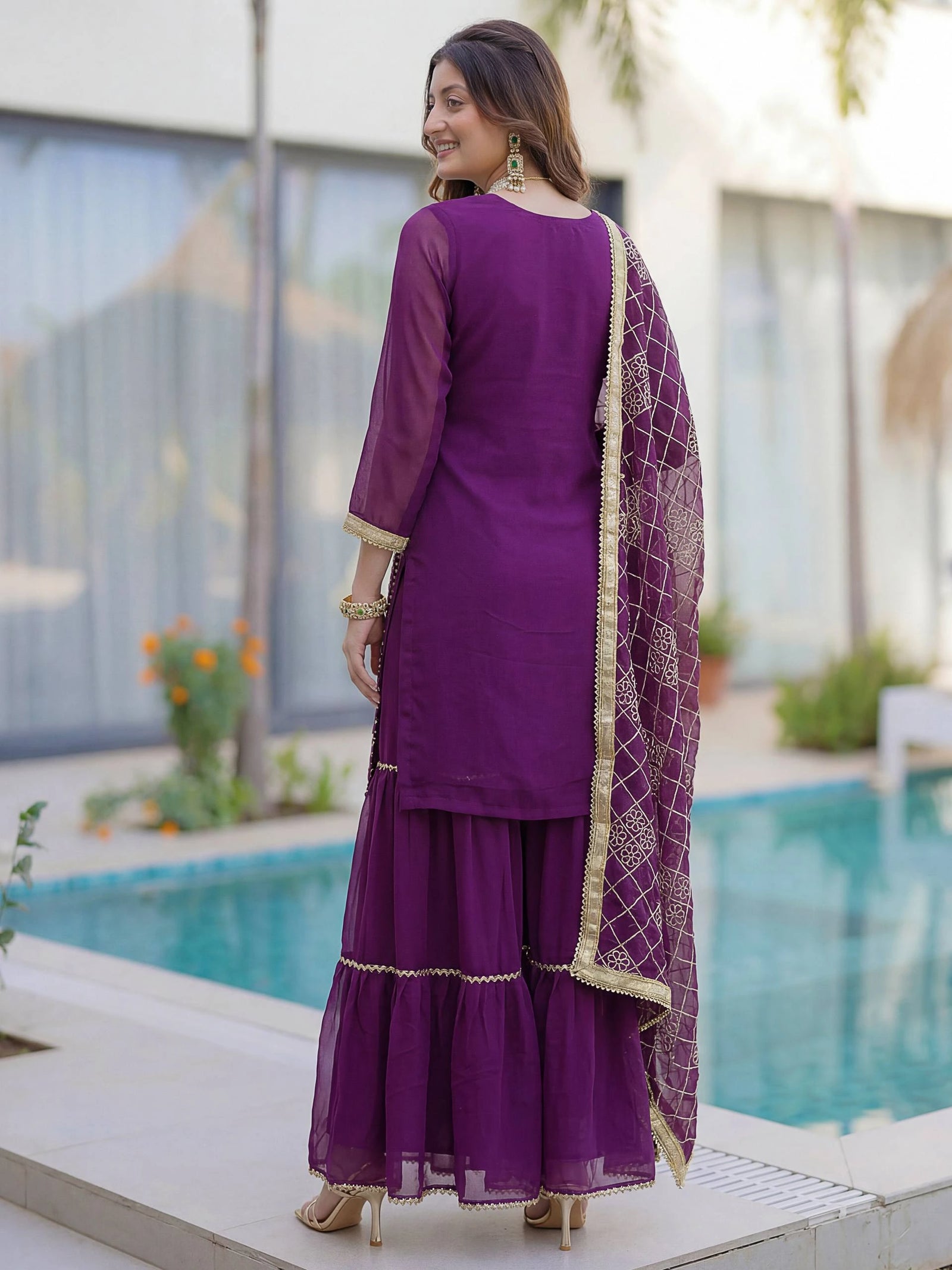 Woman in a purple traditional outfit standing by a pool
