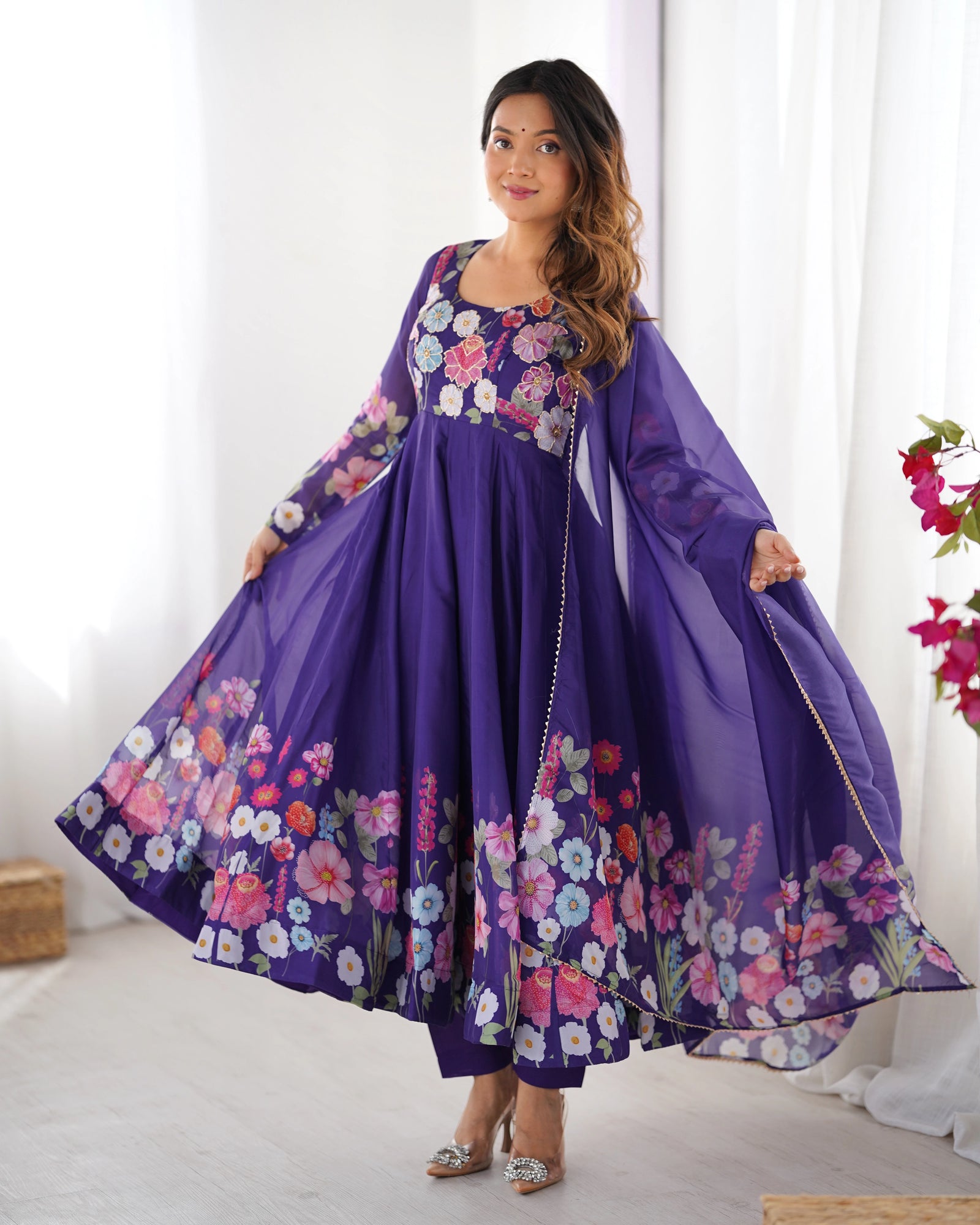 Woman wearing a purple floral dress in a bright room