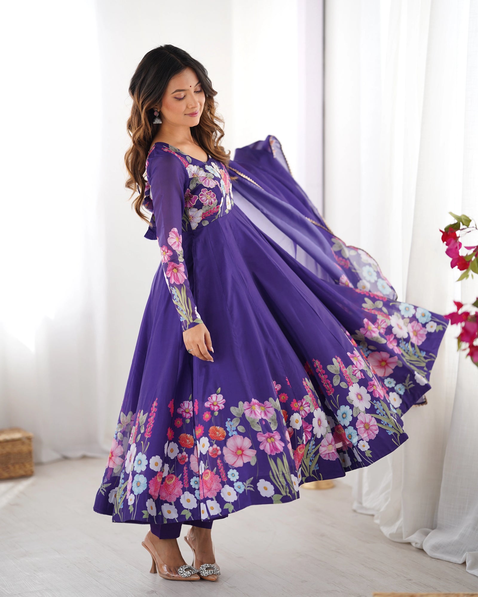 Woman wearing a purple floral dress in a bright room