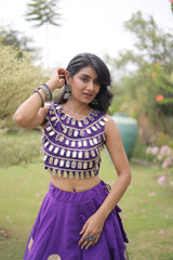 Elegant purple lehenga choli featuring a sleeveless mirror work blouse and a flared skirt with bold golden polka dot motifs.