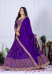 Woman wearing a purple embroidered saree with a white wall background