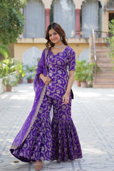 Woman in a purple traditional outfit standing outdoors.