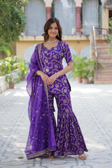 Woman in a purple traditional outfit standing outdoors.