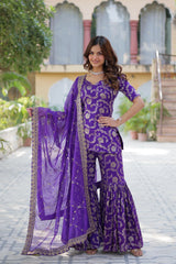 Woman in a purple traditional outfit with a matching dupatta standing outdoors.