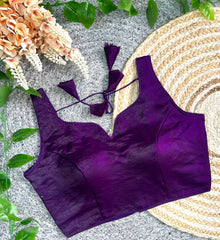 Purple bikini set on a textured surface with flowers and leaves.