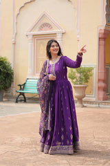 Woman in a purple traditional outfit standing in front of a decorative building.