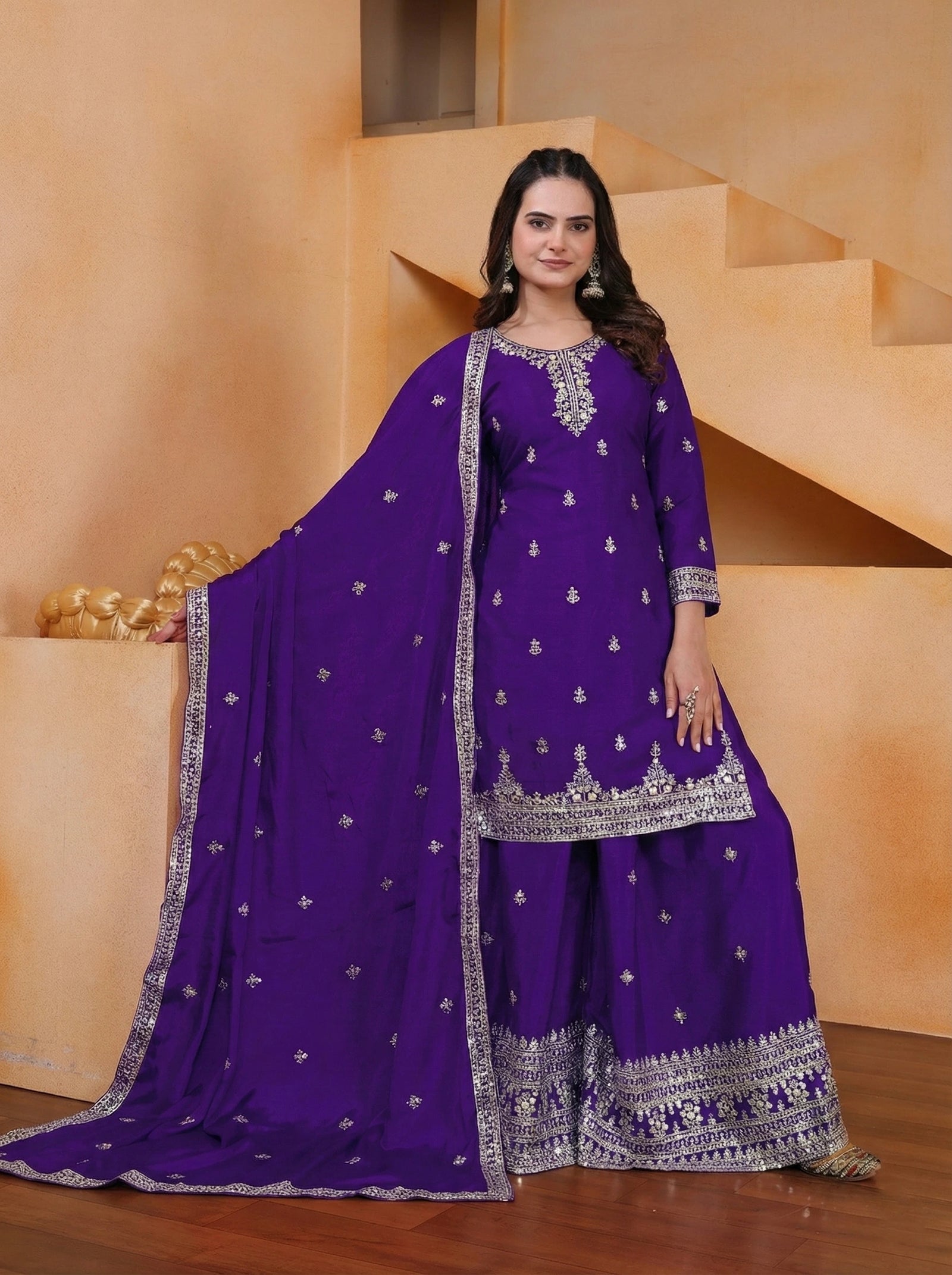 Woman wearing a purple traditional outfit with silver embroidery in an indoor setting.