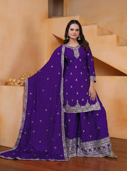 Woman wearing a purple traditional outfit with silver embroidery in an indoor setting.