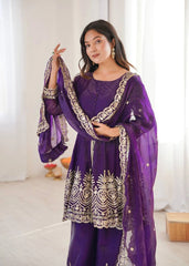 Woman wearing a purple traditional outfit with gold embroidery indoors.