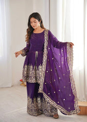 Woman wearing a traditional purple outfit with intricate designs indoors.