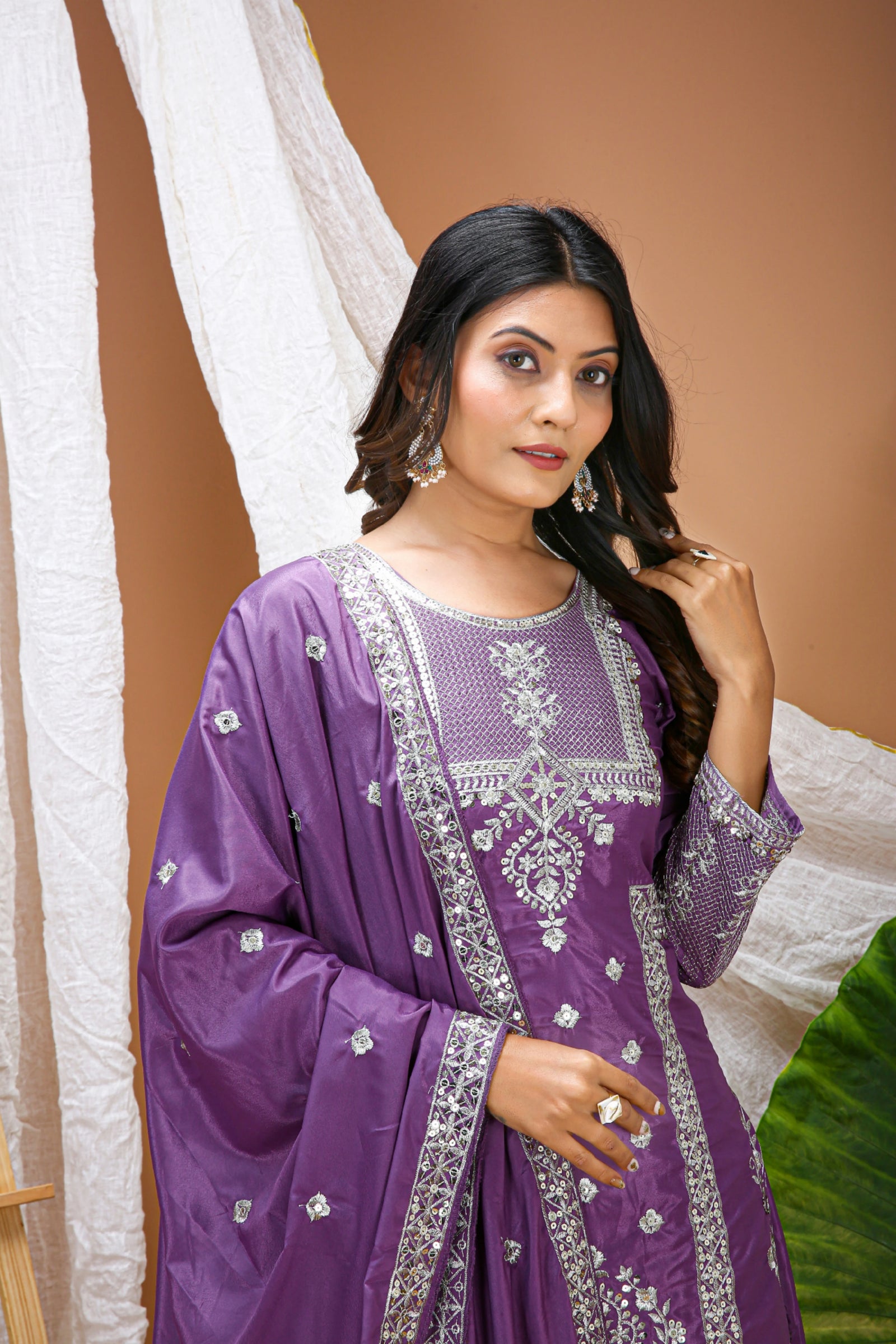 Woman wearing a purple traditional outfit with white embroidery against a beige background