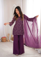 Woman in a purple traditional outfit with a matching dupatta in a bright room.