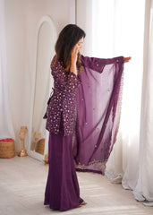 Woman in a purple outfit with a matching scarf in a room with white curtains.