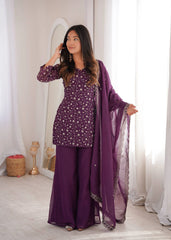 Woman in a purple traditional outfit with a matching dupatta in a well-lit room.