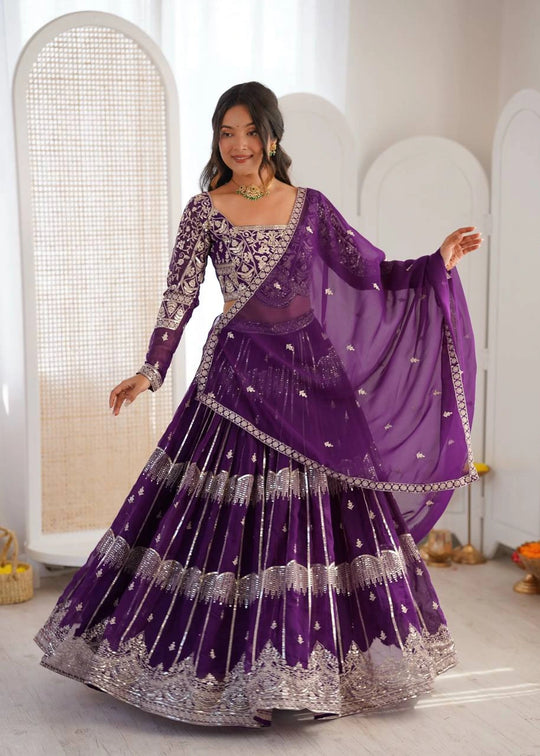 Woman wearing a traditional purple and silver dress with a matching dupatta in a neutral setting.
