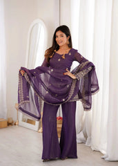 Woman in a purple traditional outfit with a matching dupatta in a bright room.
