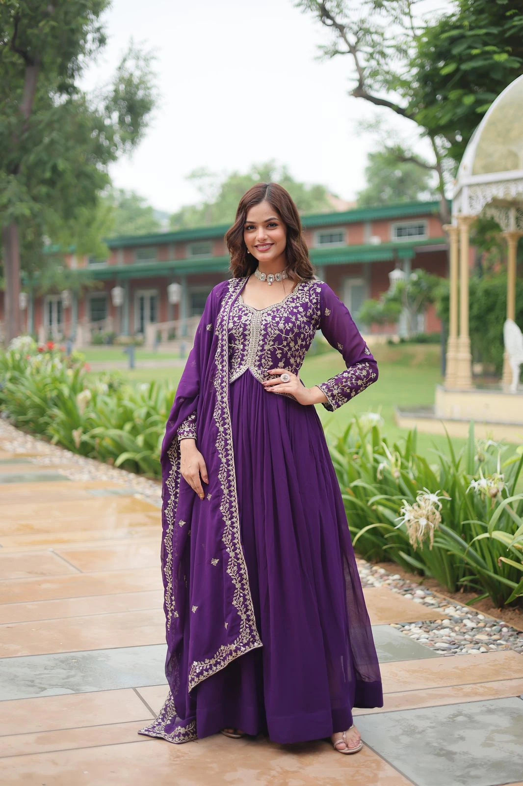 Woman in a purple traditional outfit standing in a garden setting