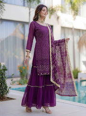 Woman in a purple traditional outfit with a matching dupatta standing by a pool.