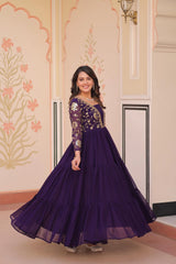 Woman in a purple gown with floral patterns standing in a decorated room.