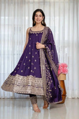 Woman in a purple traditional outfit with gold embroidery against a white curtain background