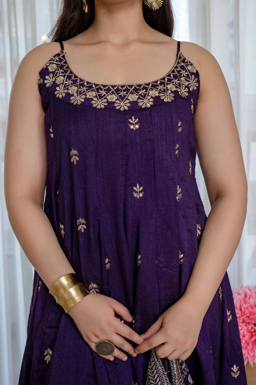 Woman wearing a purple dress with gold embroidery against a white curtain background