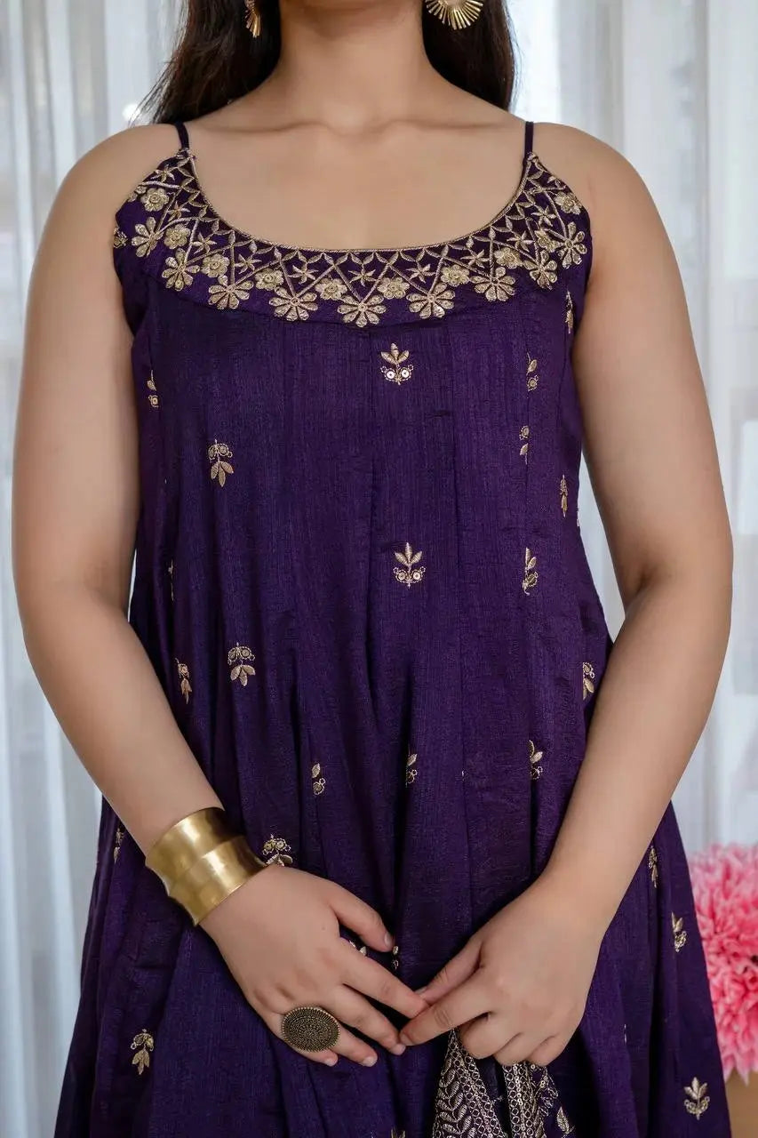 Woman wearing a purple dress with gold embroidery against a white curtain background