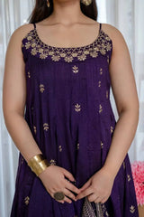 Woman wearing a purple dress with gold embroidery against a white curtain background