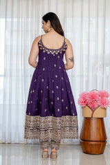 Woman wearing a purple embroidered dress with a wooden stool and pink flowers in the background