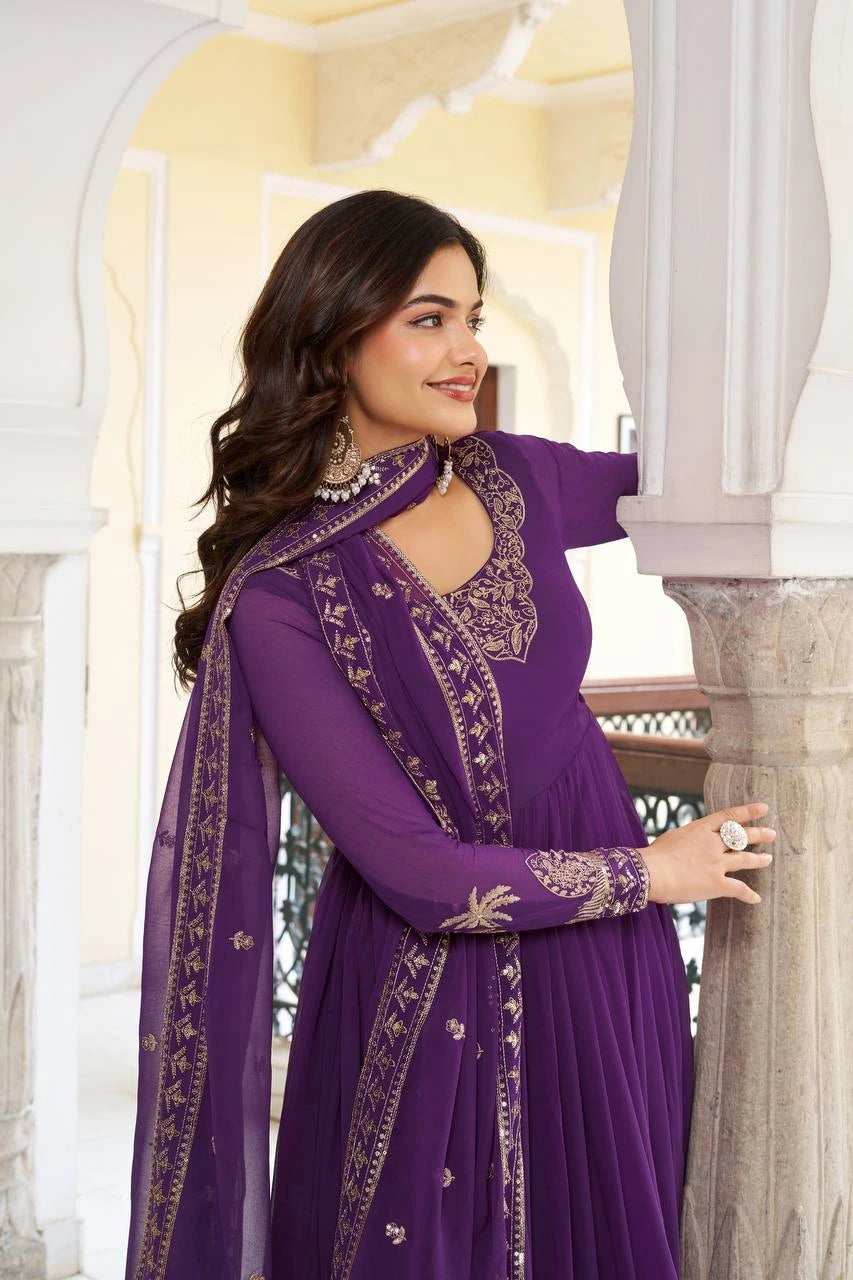 A side view of the woman leaning against a stone pillar. This angle emphasizes the long, sheer sleeves with embroidered cuffs and the way the dupatta is styled around the neck.