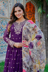Woman in a purple dress with floral shawl standing in front of a colorful architectural background