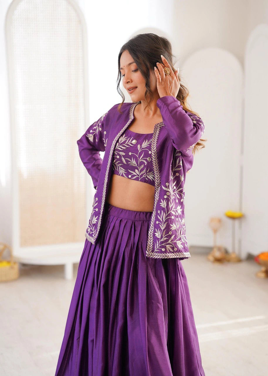 Woman wearing a purple traditional outfit with floral patterns in a minimalistic room.