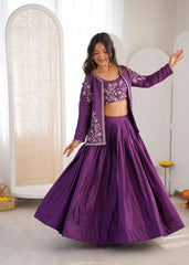 Woman in a purple traditional outfit with floral patterns in a bright room.